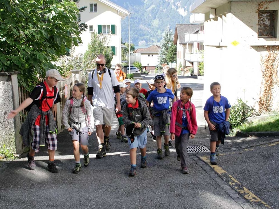 Wandergruppe mit Kindern im Dorf unterwegs.