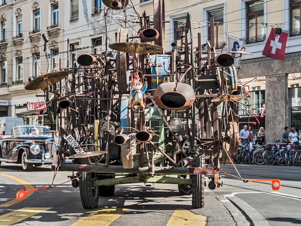 Das scheppernde Tinguely-Kunstwerk auf vier Rädern befährt eine Strasse in Basel.