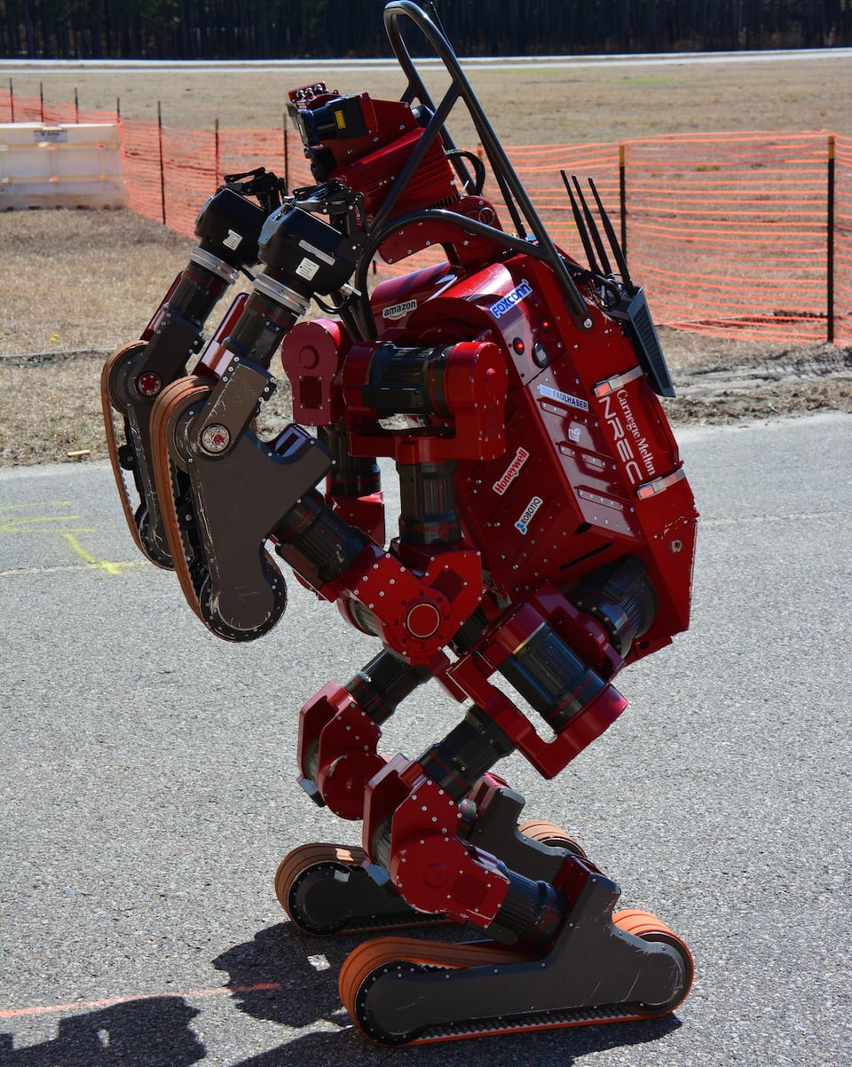 Ein Roboter rollt auf kleinen Raupen über Asphalt.