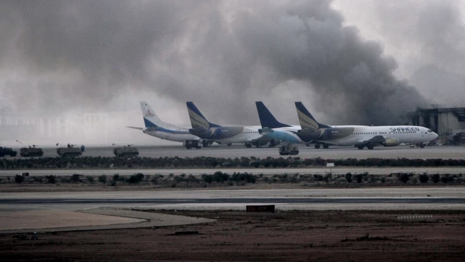 Hinter Flugzeugen steigt Rauch aus Airport-Gebäuden