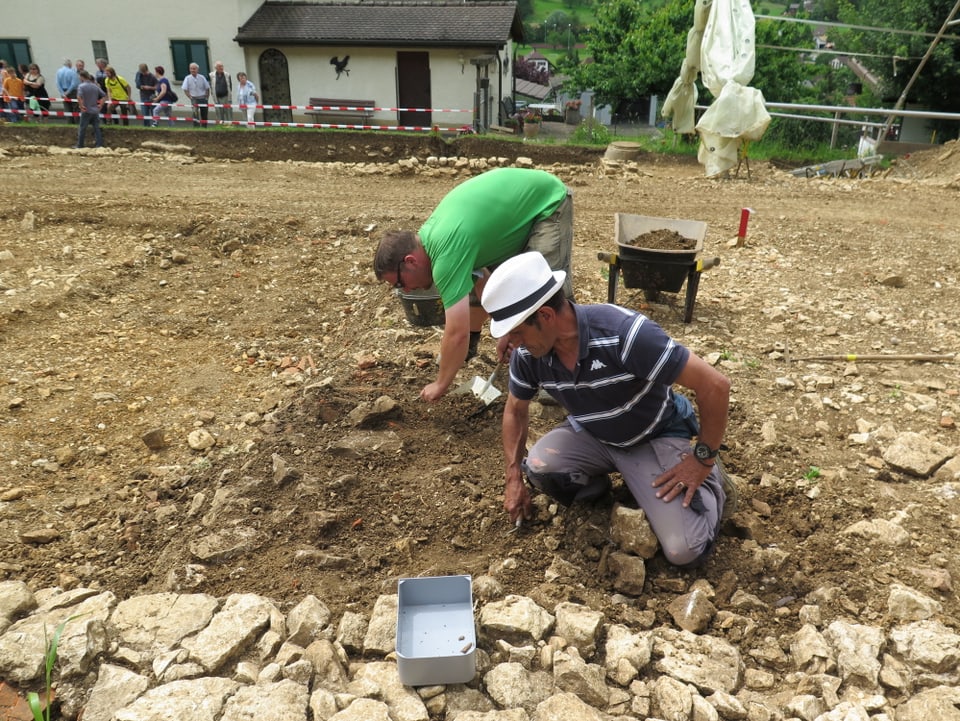 Zwei Arbeiter der Kantonsarchäologie graben in der steinigen Erde
