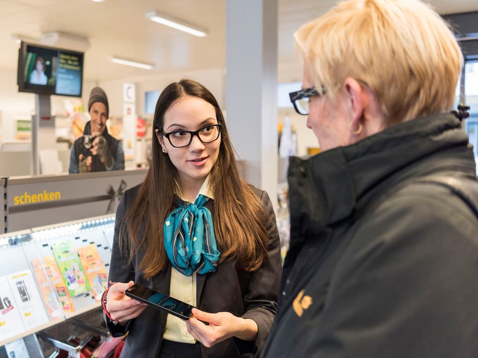 Verkaufsgespräch in einem Laden: Eine junge Frau zeigt einer Kundin ein Smartphone.