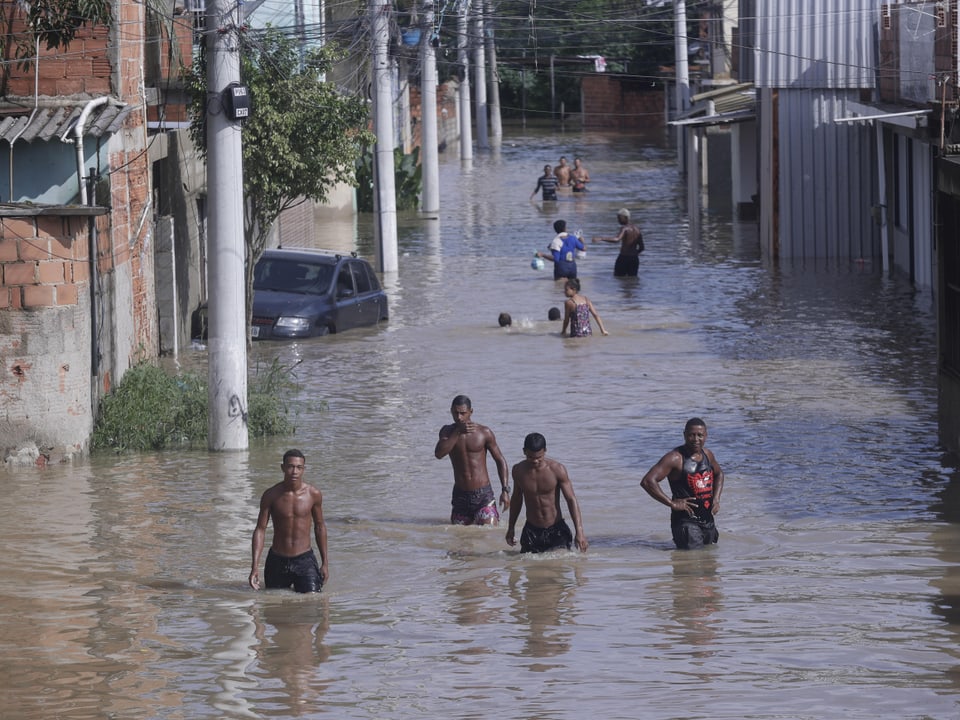 Menschen waten durch eine überflutete Strasse.