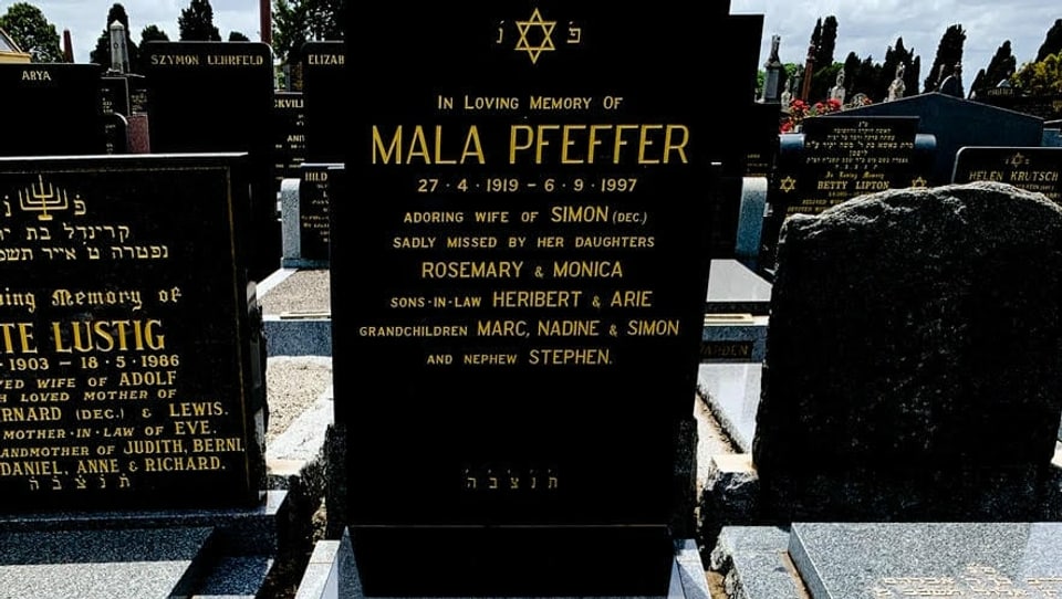 Ein schwarzer Grabstein mit der Inschrift «In Loving Memory Of Mala Pfeffer» ist im Fokus des Bilds.
