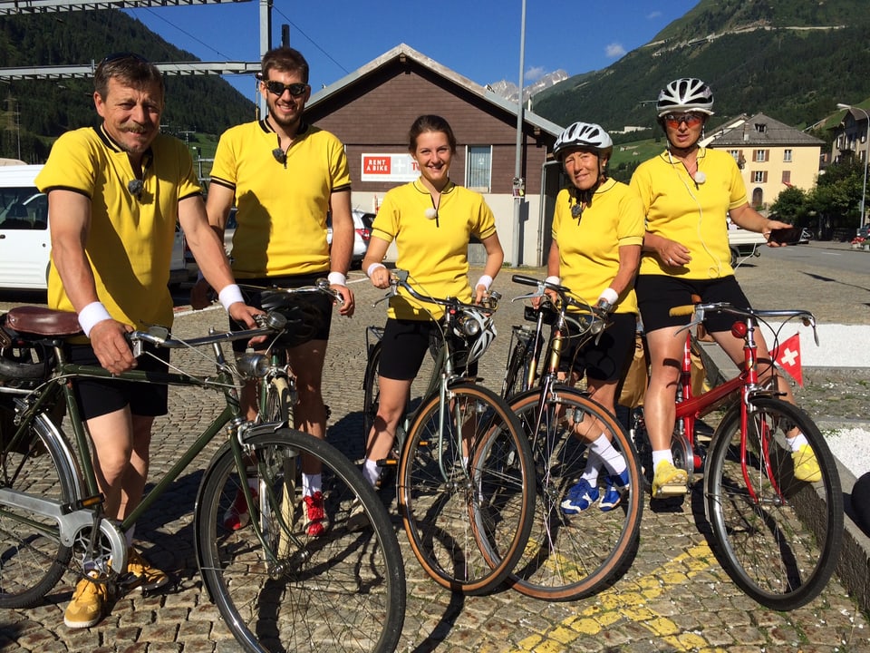 Die Gotthardabenteurer posieren in gelben Shirts und mit alten Fahrrädern.