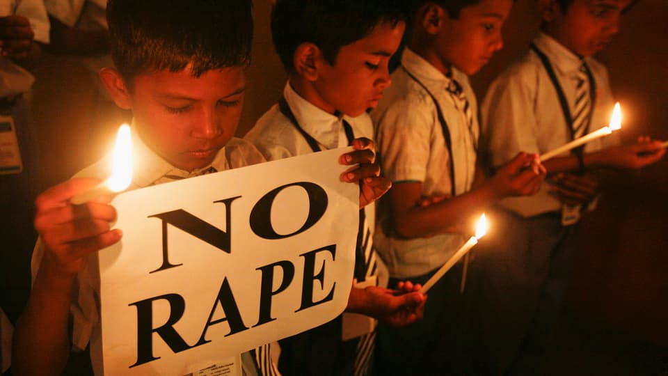 Schüler mit Kerzen halten ein Transparent mit der Aufschrift «No Rape».