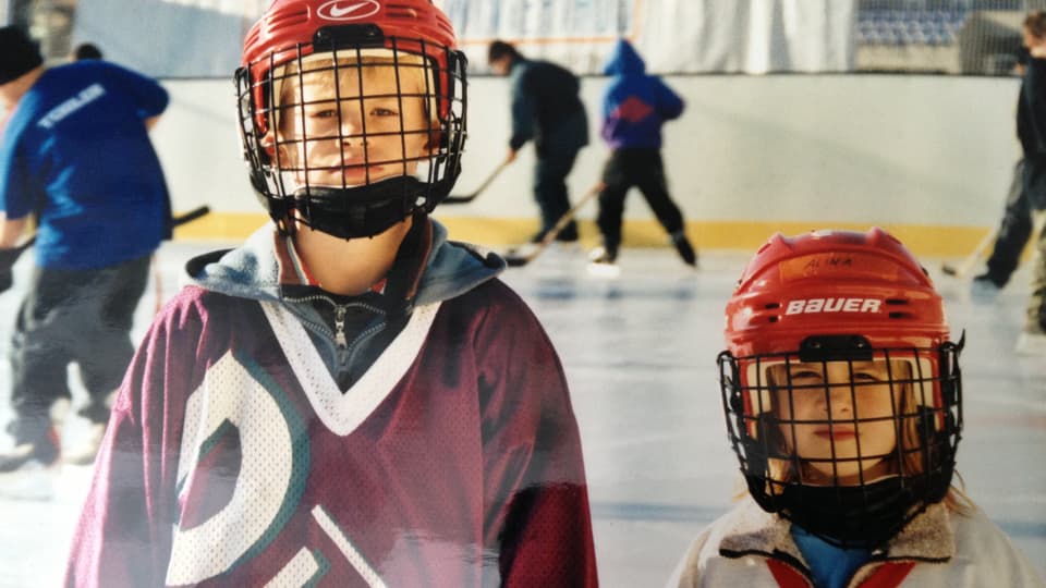 Eishockeyprofis und Geschwister Mirco Müller und Alina Müller als Kinder mit Helm und Ausrüstung auf dem Eisfeld.