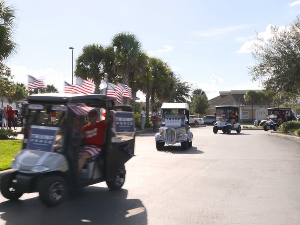 mit Flaggen und Plakaten geschmückte Golfwagen in einer Seniorensiedlung