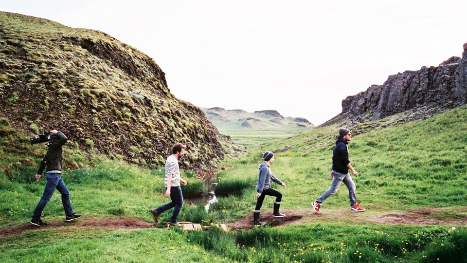 Vier Personen laufen durch eine grüne Landschaft.
