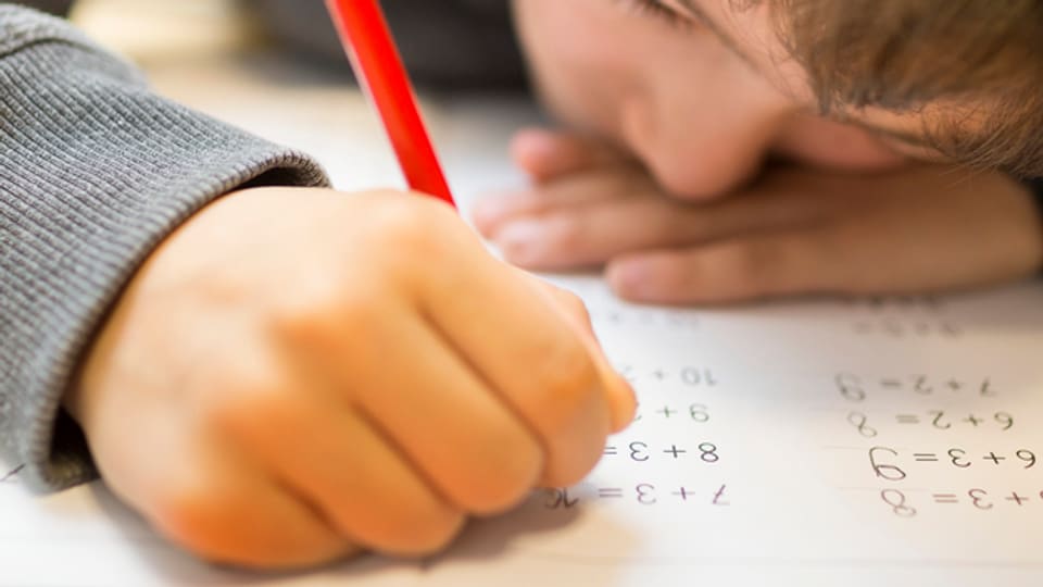 Ein Schüler löst mit einem Bleistift Mathematik-Aufgaben.