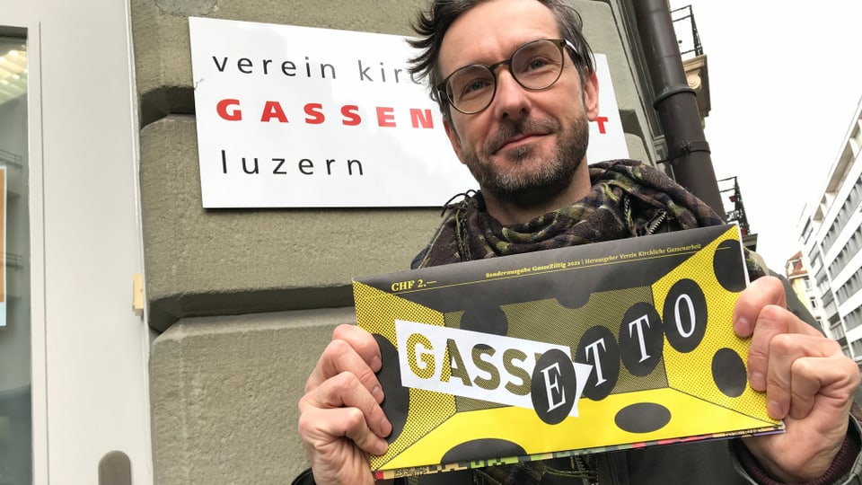 Roger Lütolf vom Verein Kirchliche Gassenarbeit Luzern mit einer Comic-Spezialausgabe der "Gasseziitig" in der Hand.