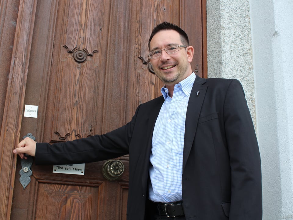 Pfarrer Rolf Kalbermatter vor der Türe der Pfarrkirche.