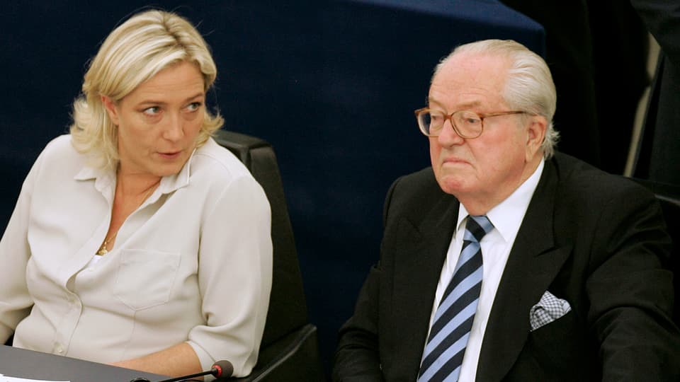 Marine Le-Pen blickt seitlich und kühl auf ihren Vater Jean-Marie. Dieser schaut nach vorne. 