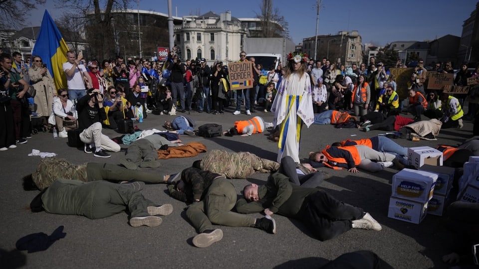 Menschen mit Militärbekleidung liegen auf dem Boden bei der künstlerischen Darstellung.
