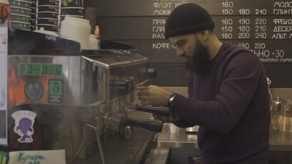 Ein Mann mit schwarzer Mütze bereitet Kaffee zu.