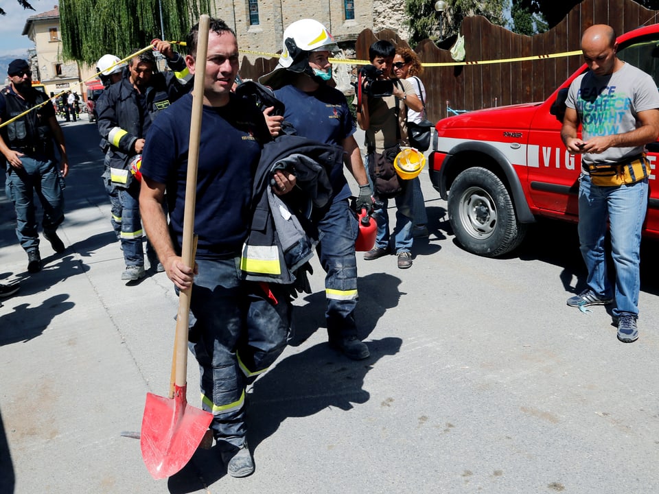 Feuerwehrleute mit Schaufeln und Rettungsmaterial.