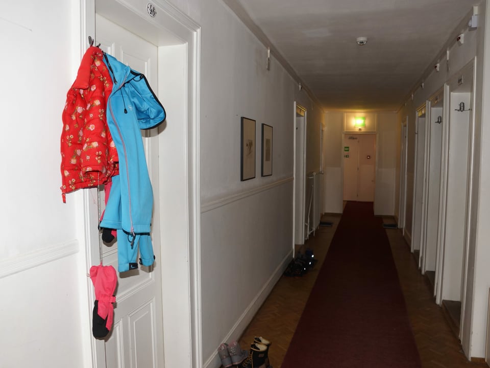 Hotelgang mit Kleidern die vor einer Zimmertüre hangen.