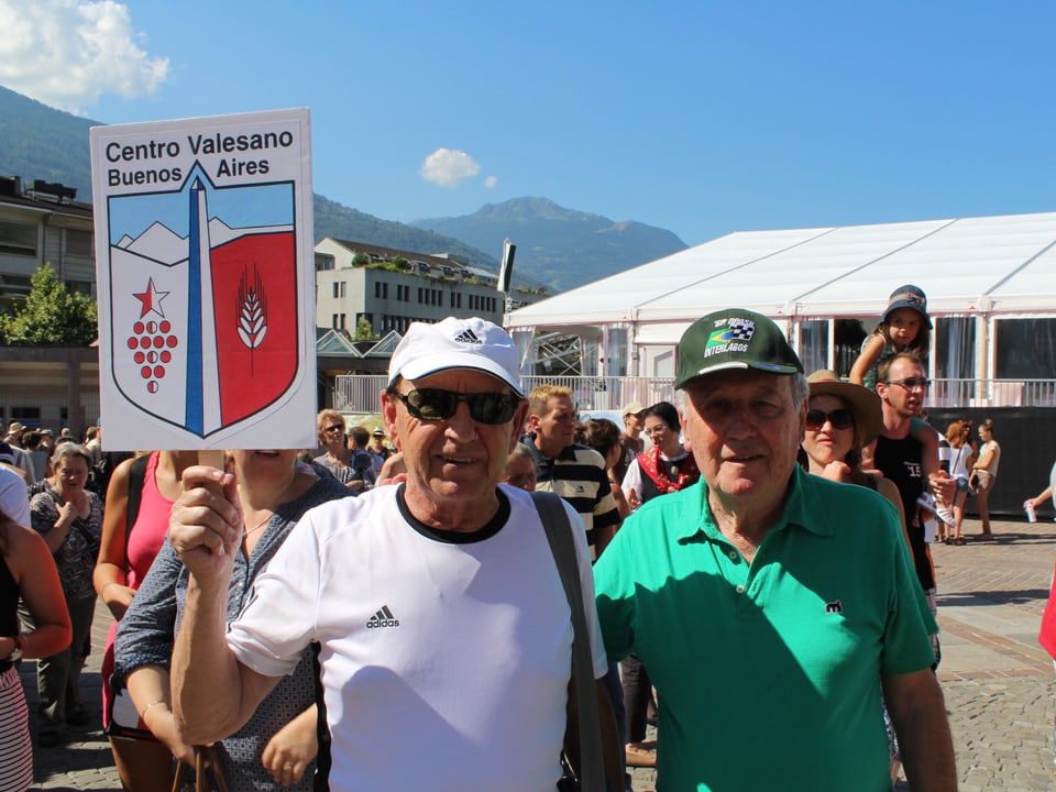 Zwei Männer, halten ein Schild mit Wappen und der Aufschrift «Centro Valesano Buenos Aires» in die Kamera.