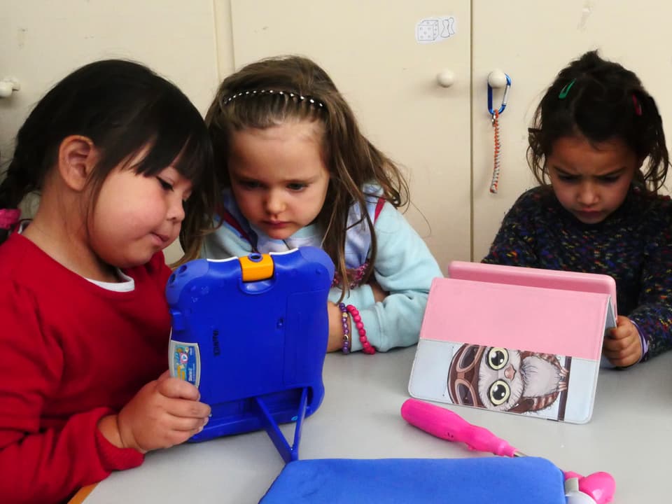Drei Mädchen schauen sich Tablet-Computer an.