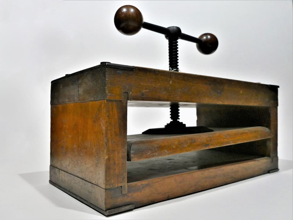 Eine Handpresse aus Holz und Metall.