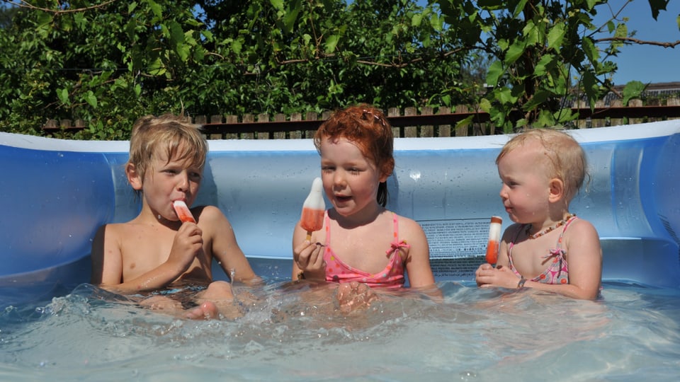 Doppelt hält besser - Kinder erfrischen sich im kühlenden Wasser mit einem kühlenden Eis.