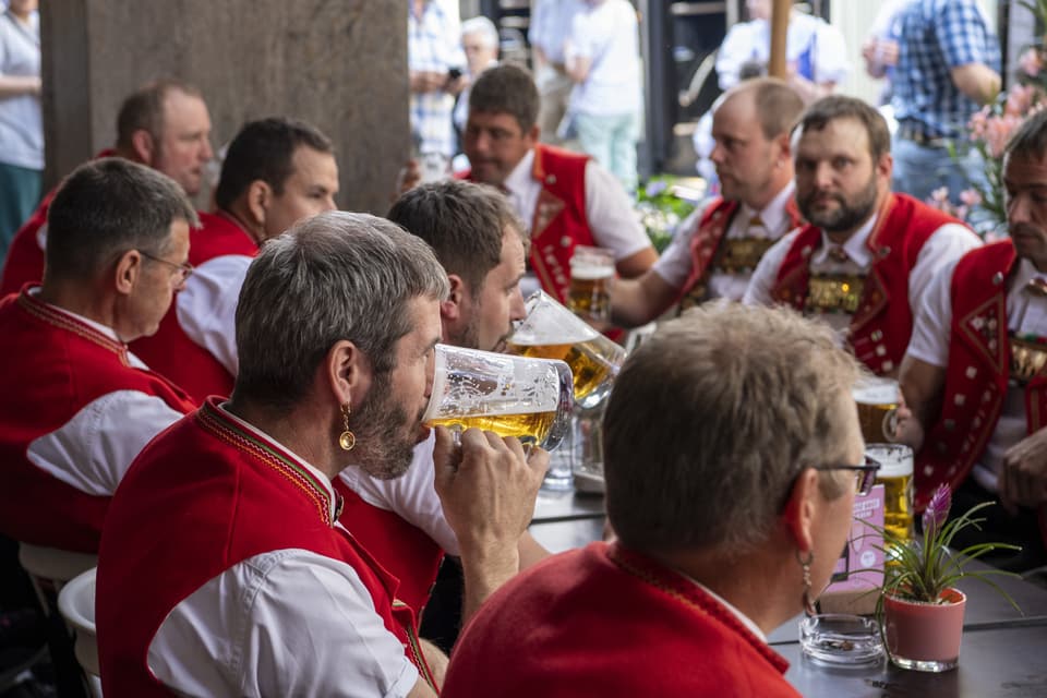 Eine Gruppe von Jodler sitzt an einem Tisch und trinkt Bier.
