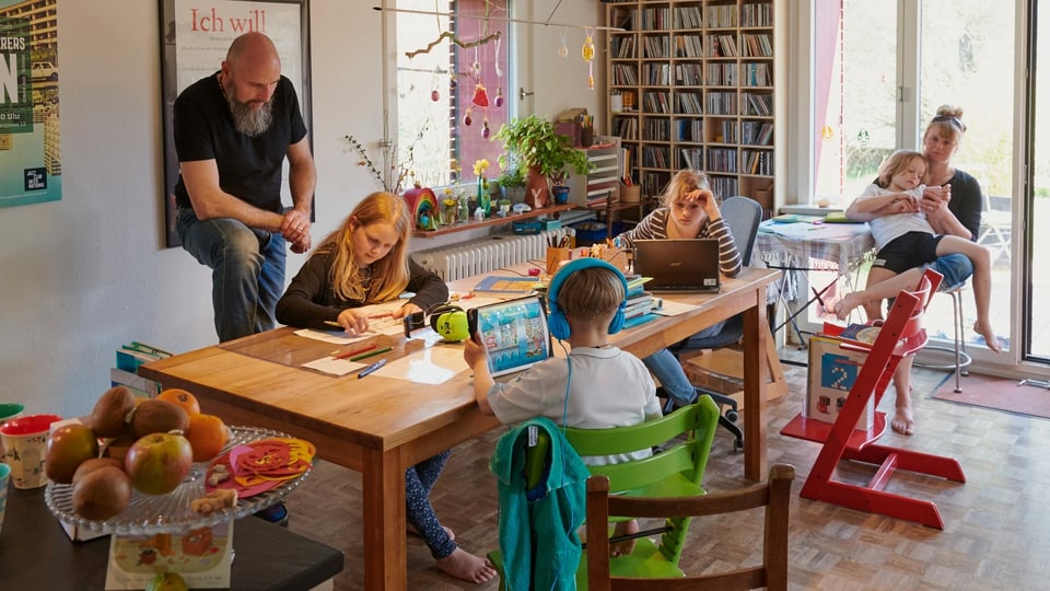 Eltern und Kinder sitzen rund um einen Tisch.