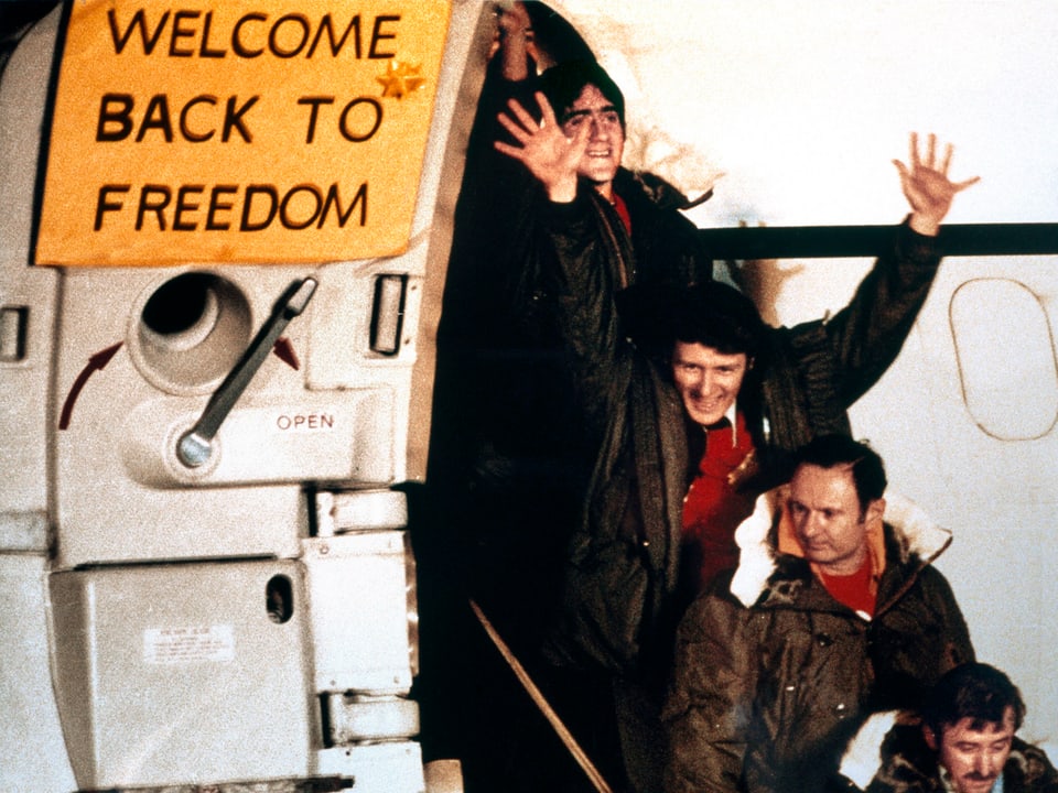 Die Freigelassenen steigen auf dem Frankfurter Rhein-Main-Flughafen aus einem Flugzeug, an dessen geöffneter Tür steht "Welcome back to freedom"