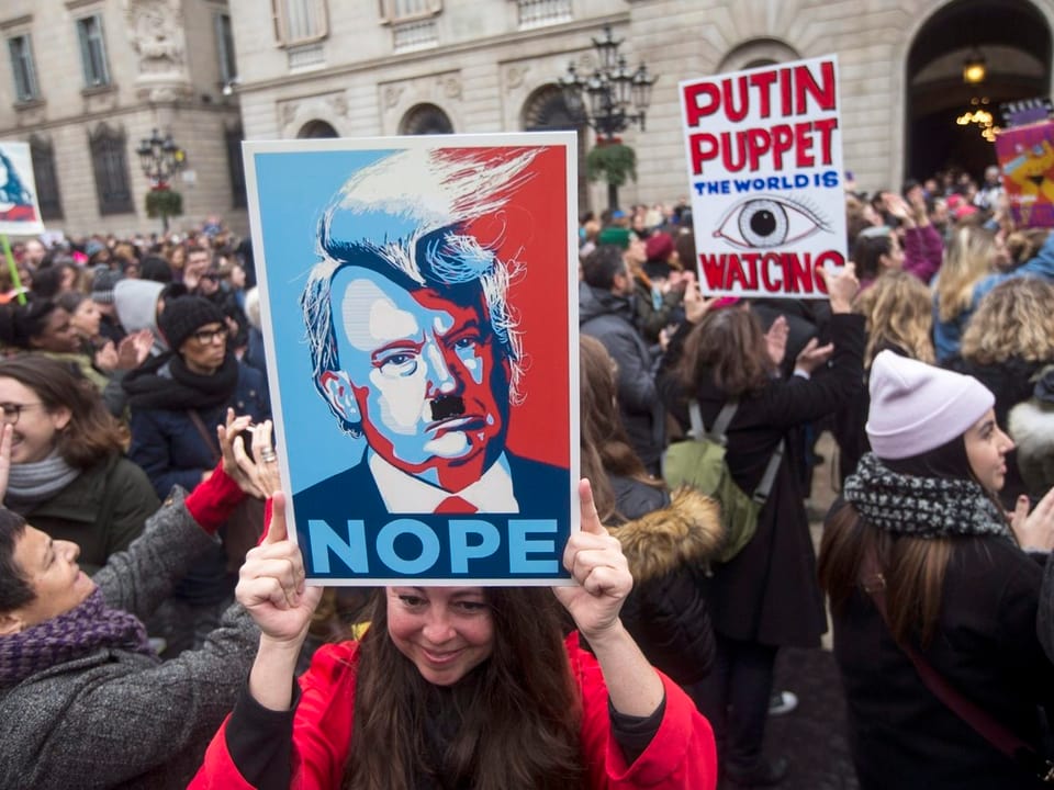Demonstrantin mit Foto von Trump mit Hitler-Schnauz.