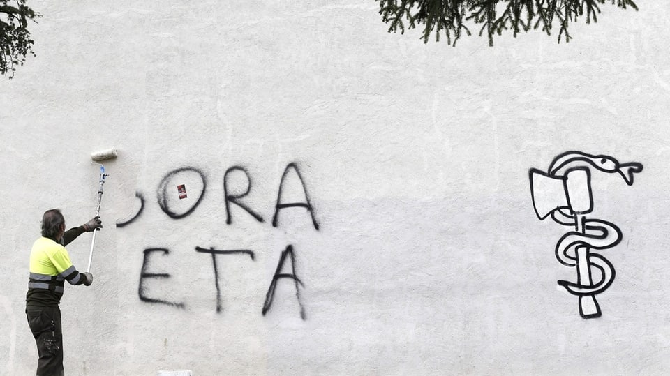 Eine Person putzt ein Graffiti mit der Aufschrift «Gora ETA» weg.