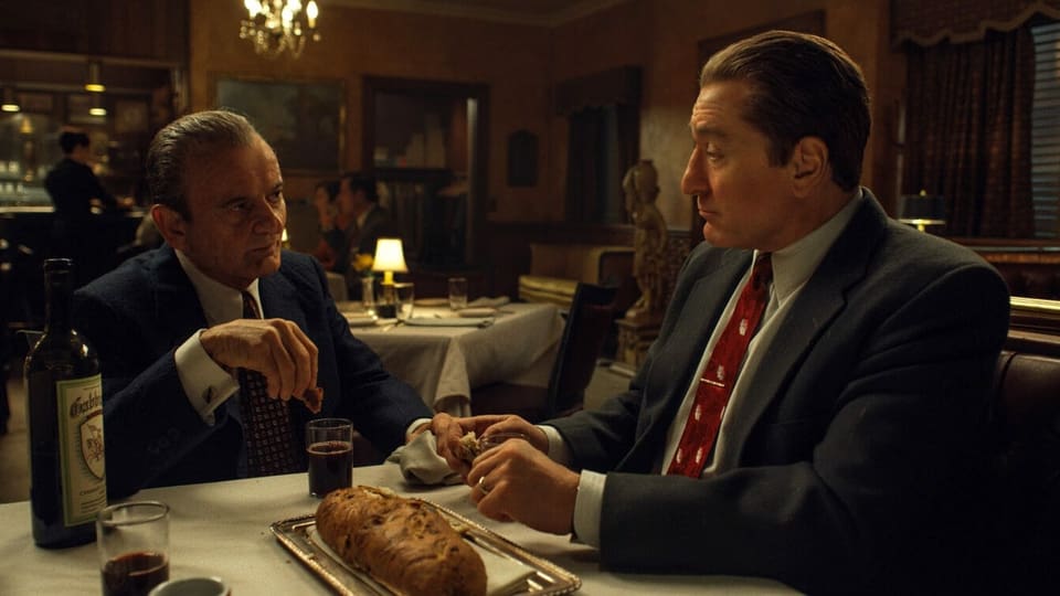 Filmszene aus The Irishman: Zwei Mänenr sitzen im Restaurant an einem Tisch. 
