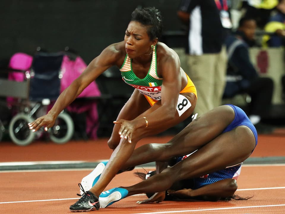 Athletin stolpert über eine am Boden liegende Konkurrentin