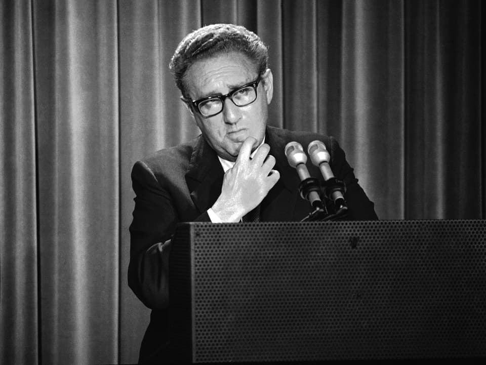Schwarzweiss-Foto von Henry Kissinger hinter einem Rednerpult