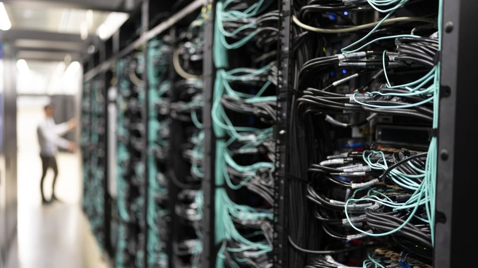 Ein Mitarbeiter arbeitet am Supercomputer Alps am nationalen Hochleistungsrechenzentrum CSCS ; zu sehen sind viele Kabel