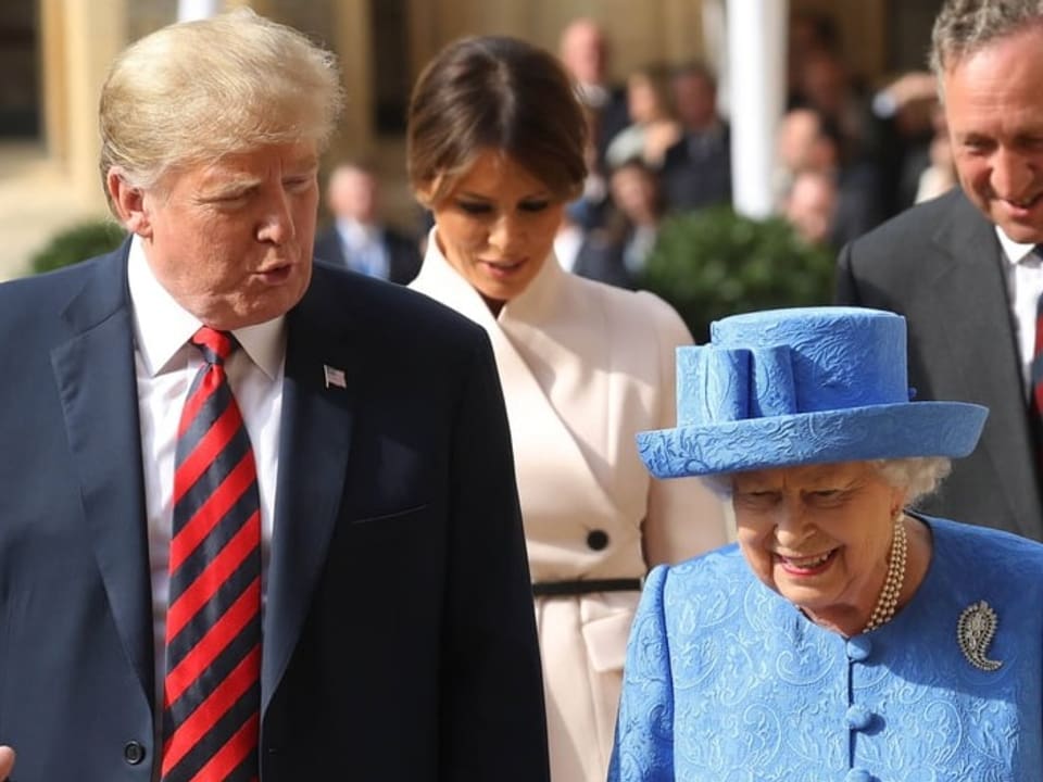 Donald Trump läuft neben Queen Elizabeth II. Im Hintergrund ist Melania Trump zu sehen.