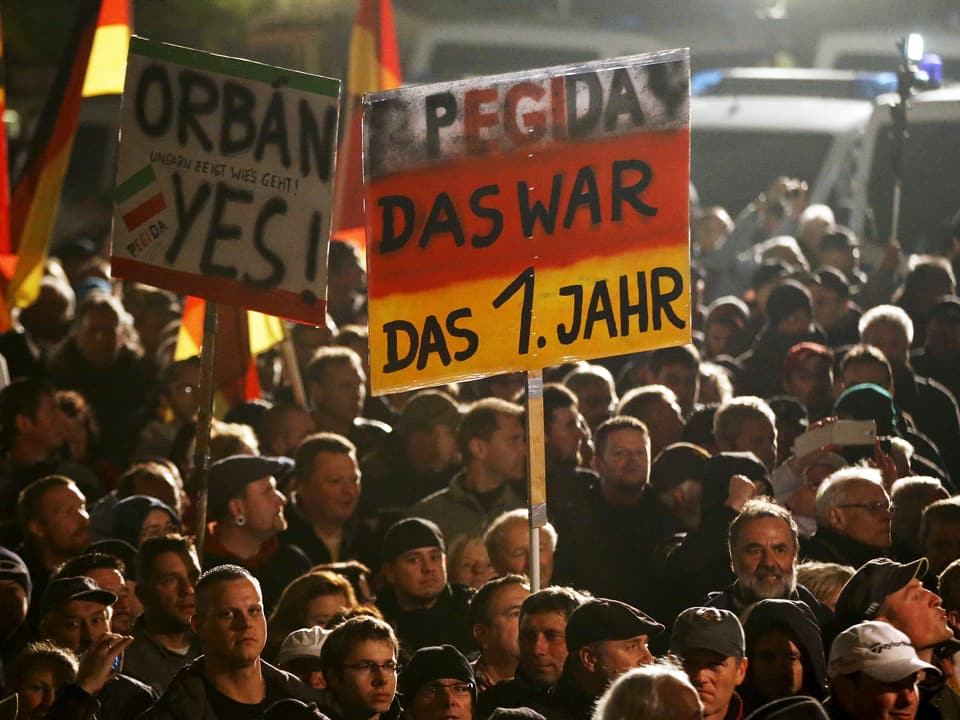 Pegida-Demonstranten am ersten Jahrestag der Kundgebungen. Teilnehmer tragen ein Plakat mit der Aufschrift «Pegida, das war das 1. Jahr» und «Orban, yes».