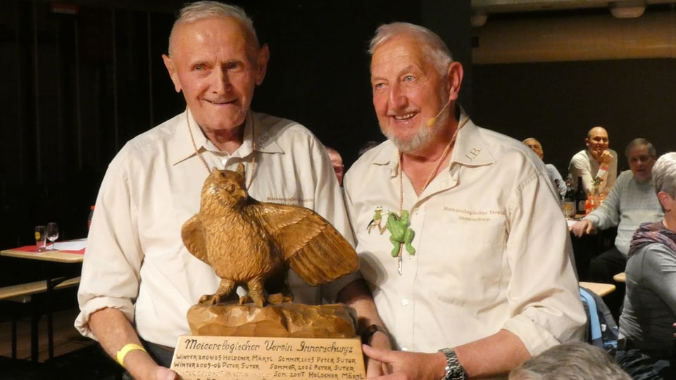 Zwei Männer mit einem Adler aus Holz.