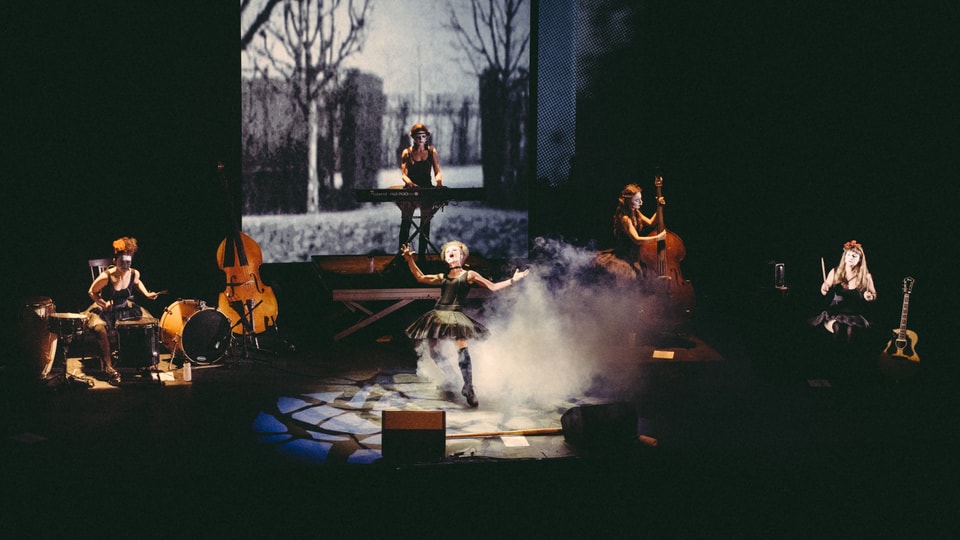 Eine Band bestehend aus fünf Frauen spielt auf einer Bühne in Rauch gehüllt.