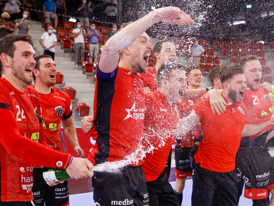 Jubelnde Pfadi-Spieler spritzen Champagner aus einer Flasche.