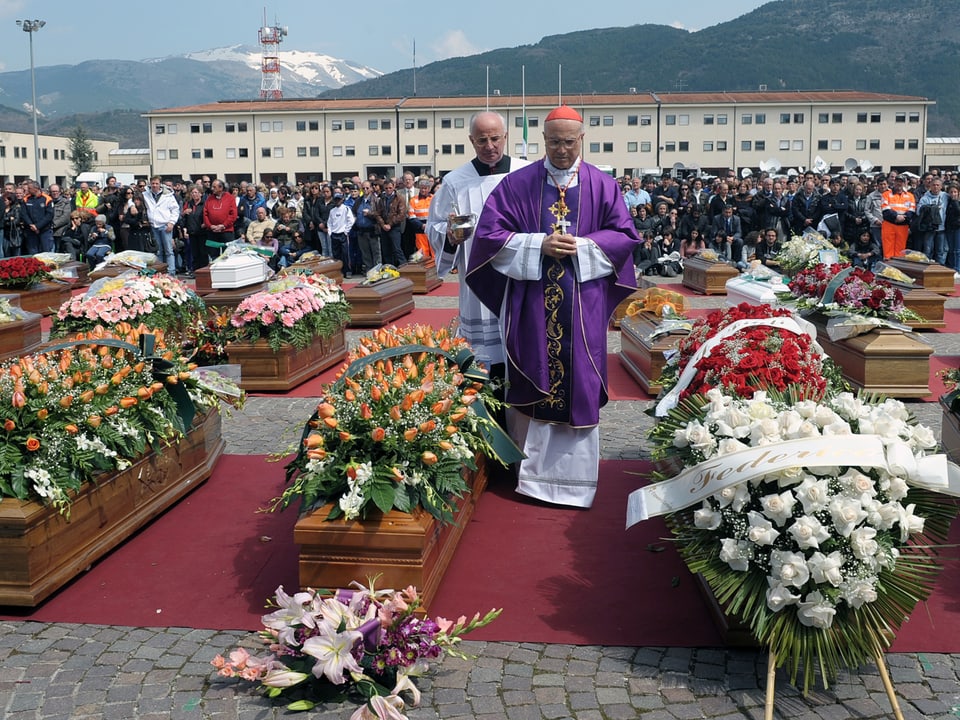 Kardinal in L'Aquila zwischen blumengeschmückten Särgen der Erdbeben-Opfer