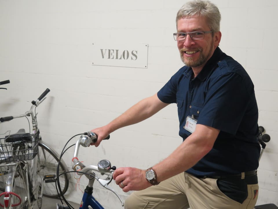 Mann auf Fahrrad steht vor einem Schild mit der Aufschrift «Velos».