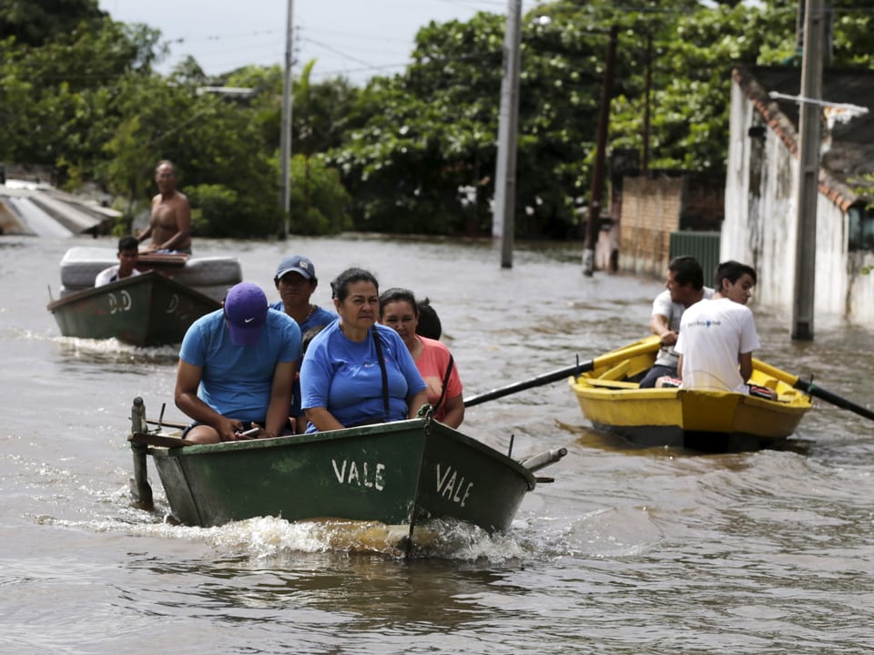 Menschen sind in den überfluteten Strassen von Asuncion in Booten unterwegs.