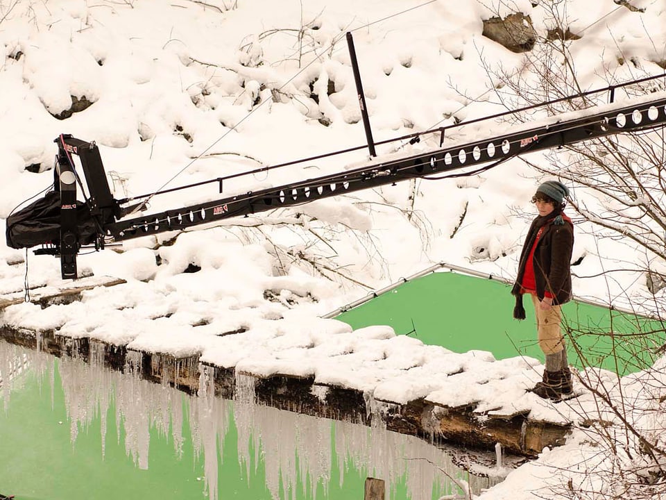 Schellenursli läuft über die verschneite Holzbrücke, darunter der Greenscreen.