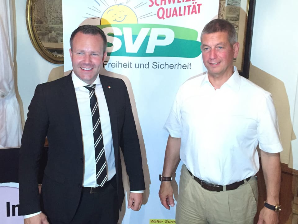 Zwei Männer vor SVP-Logo