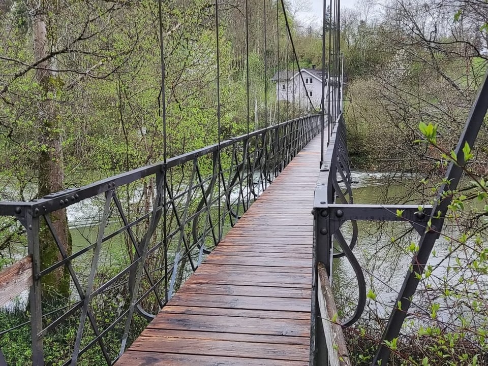 Holz-Stahlsteg über Fluss.