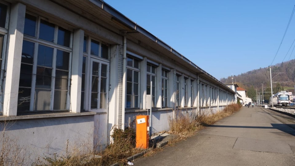 Langes Fabrikgebäude an Bahnlinie in Teufenthal