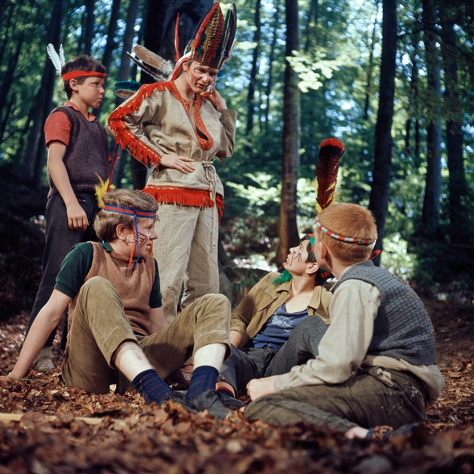 Fünf der Kummerbuben im Wald verkleidet als Indianer. Drei sitzen, zwei stehen.