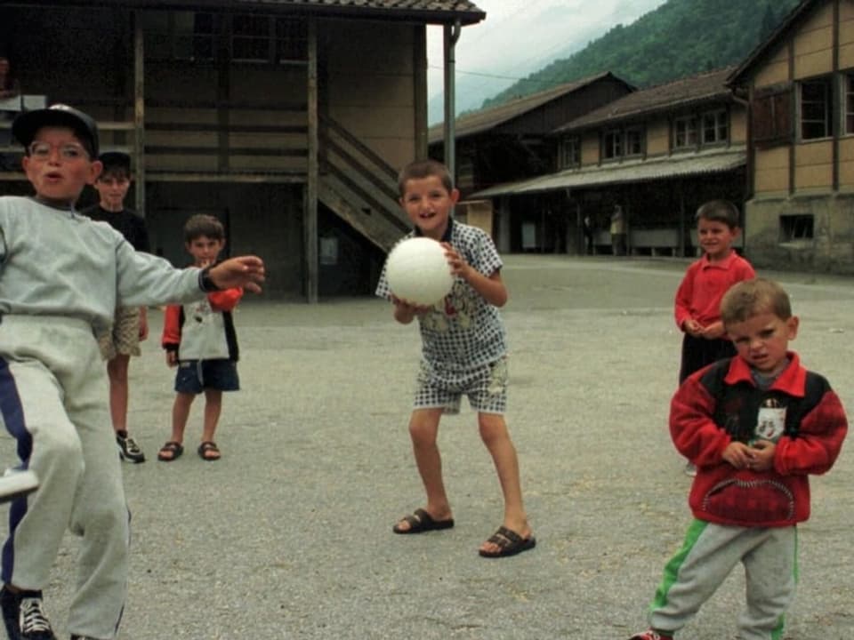 Kinder aus dem Kosovo beim Fussballspielen vor Militärbaracken im Tessin.