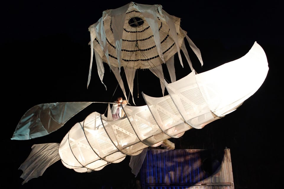 Ein leuchtendes Papierschiff fliegt durch die Luft. 