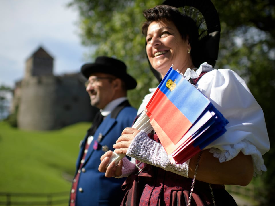 Eine Frau und ein Mann in Trachten posieren auf der Schlosswiese in Vaduz.
